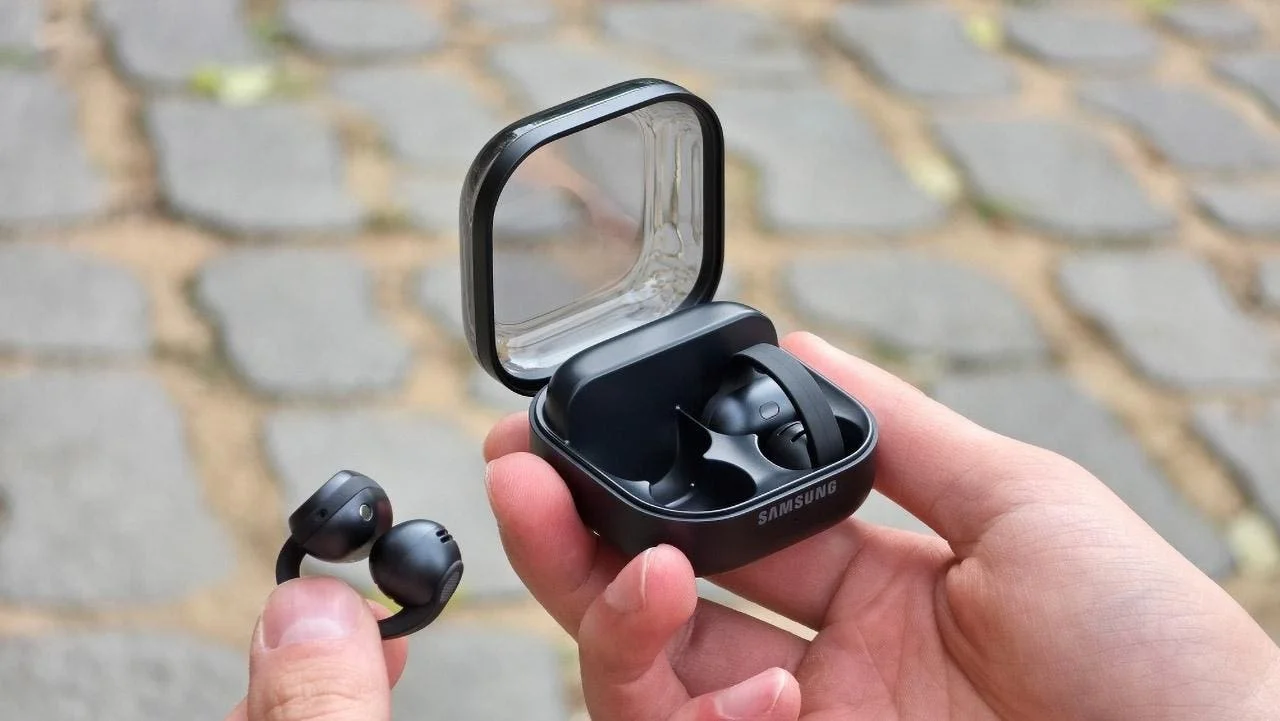 Galaxy Buds On: открытый кейс на ладони и наушник-клипса в другой руке