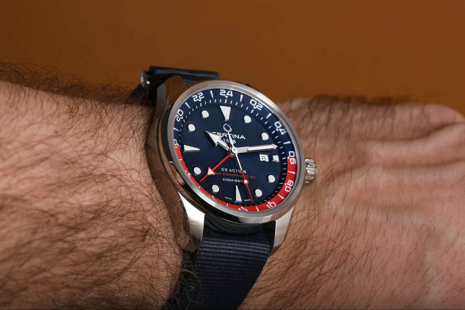 Часы Certina DS Action GMT Powermatic 80 с сине-красным безелем на мужском запястье